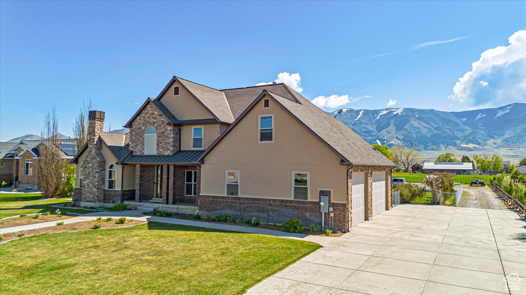 Craftsman-style house featuring stucco siding, driveway, a chimney, a front lawn, and an attached garage