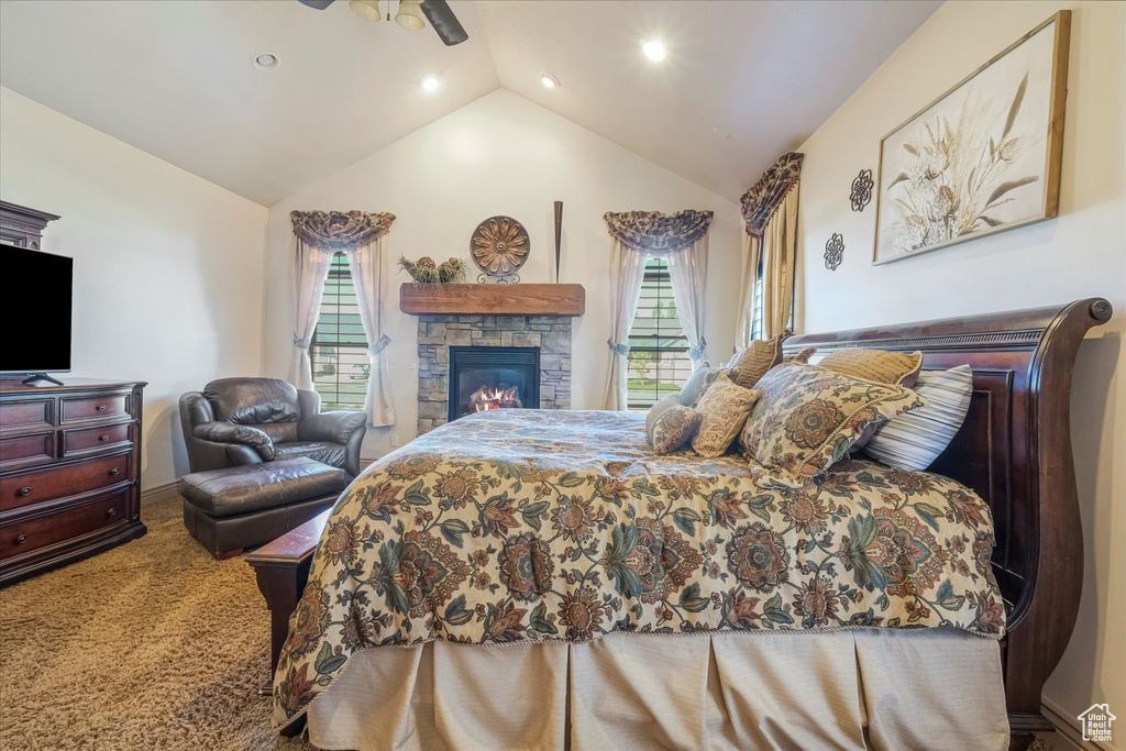 Carpeted bedroom featuring vaulted ceiling, recessed lighting, ceiling fan, and a stone fireplace