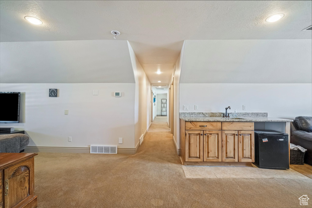 Interior space with light carpet, fridge, baseboards, and a textured ceiling