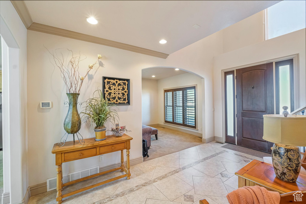 Foyer featuring arched walkways, baseboards, recessed lighting, crown molding, and inlaid floor details