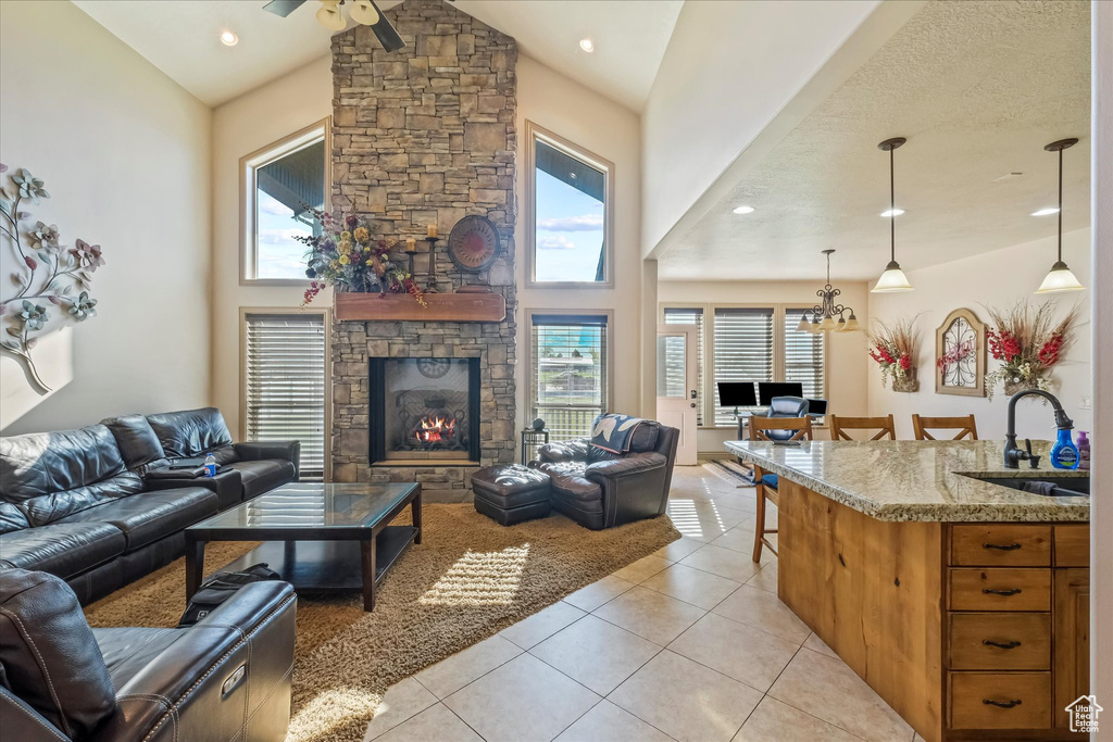Living area featuring light tile patterned flooring, ceiling fan, a fireplace, high vaulted ceiling, and recessed lighting