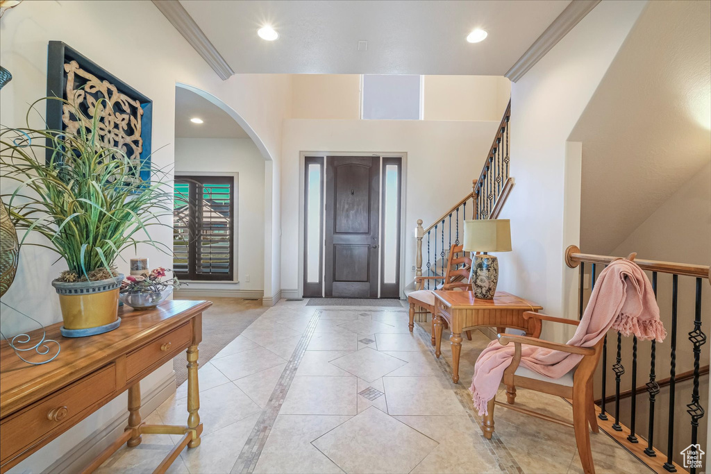 Foyer with inlaid floor details, baseboards, arched walkways, stairway, and recessed lighting