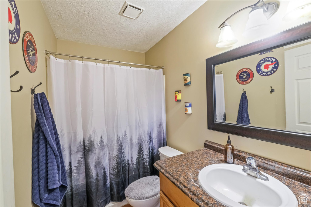 Full bathroom featuring toilet, a textured ceiling, vanity, and a shower with shower curtain