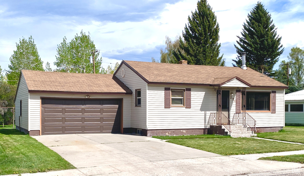 Ranch-style house with a front yard, an attached garage, concrete driveway, a chimney, and roof with shingles