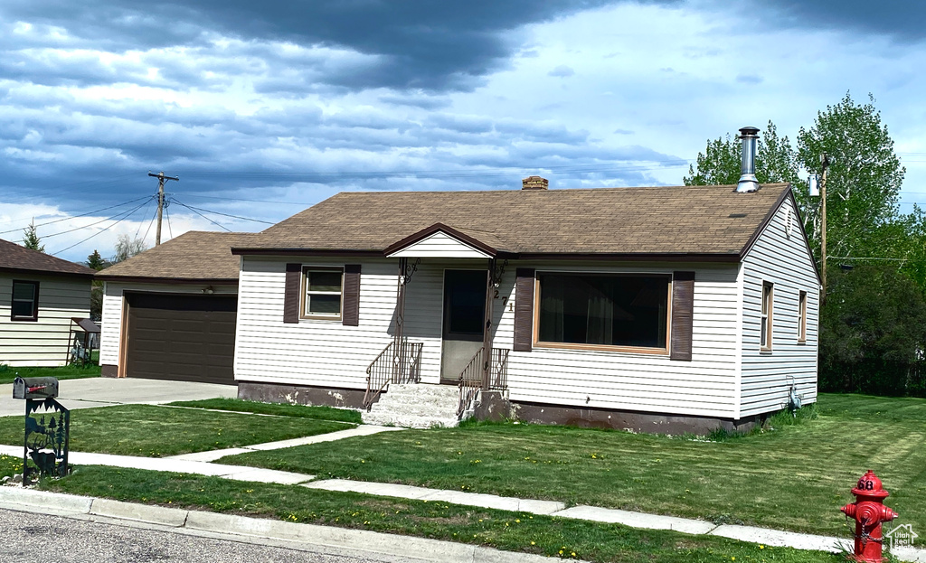 View of front of house with entry steps, a front yard, a shingled roof, and a chimney