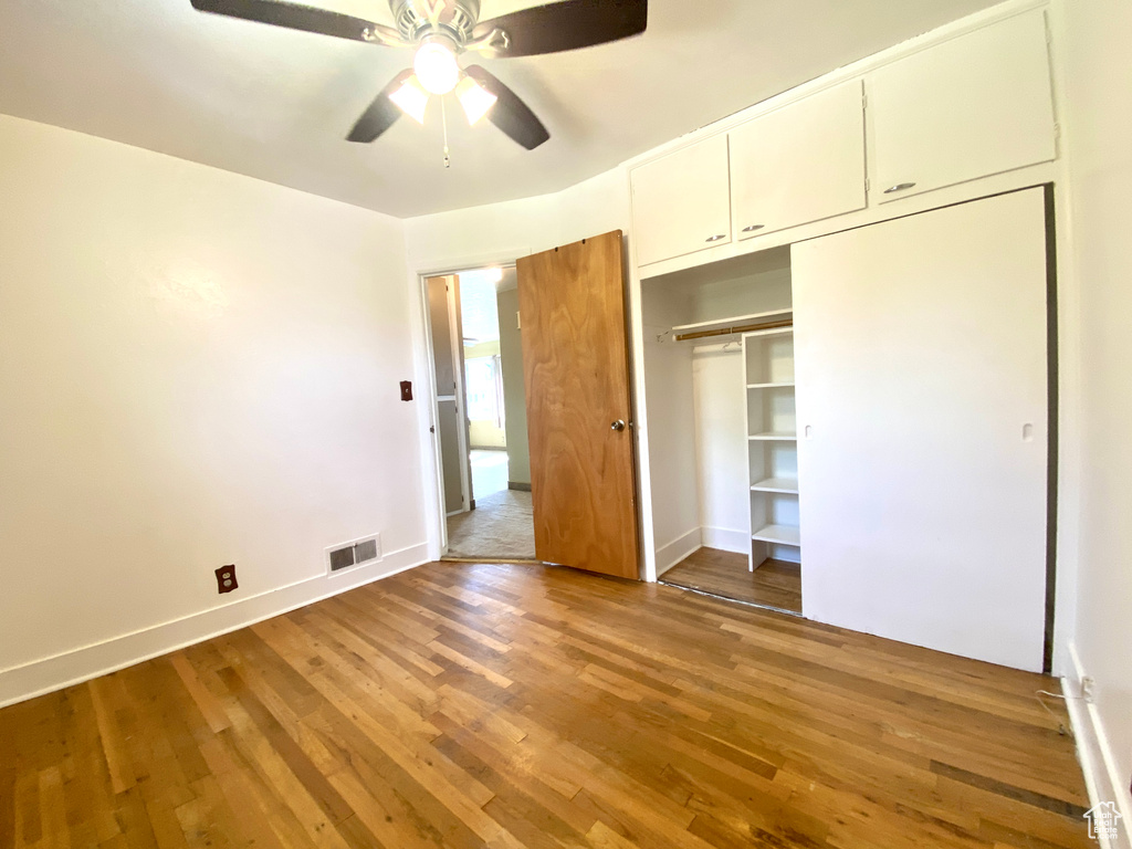 Unfurnished bedroom featuring wood finished floors, baseboards, a closet, and ceiling fan