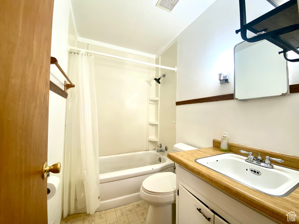 Bathroom with toilet, shower / bathtub combination with curtain, vanity, and tile patterned floors