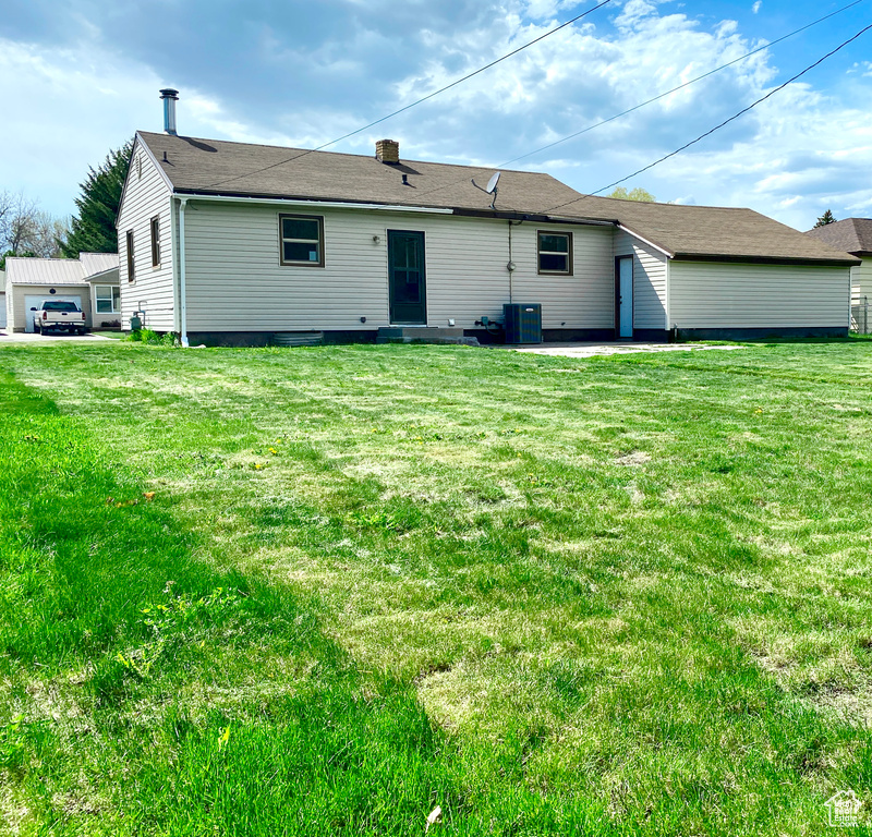 Back of property with a yard, central AC, and a chimney