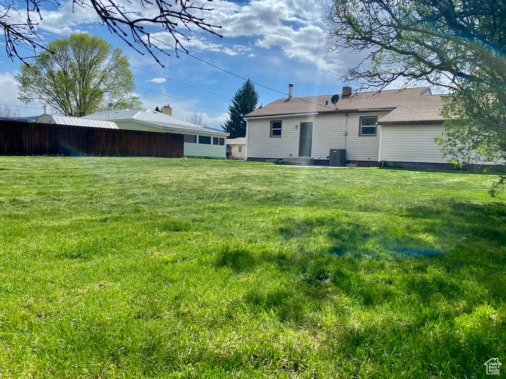 View of grassy yard with central AC unit