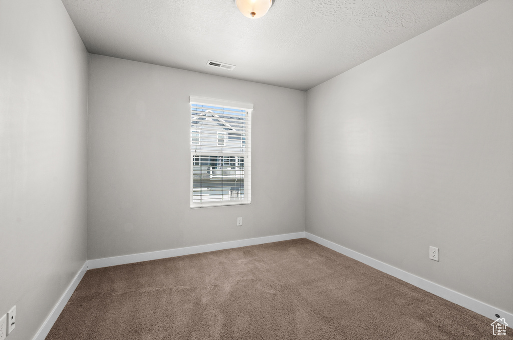 Carpeted empty room with baseboards and a textured ceiling