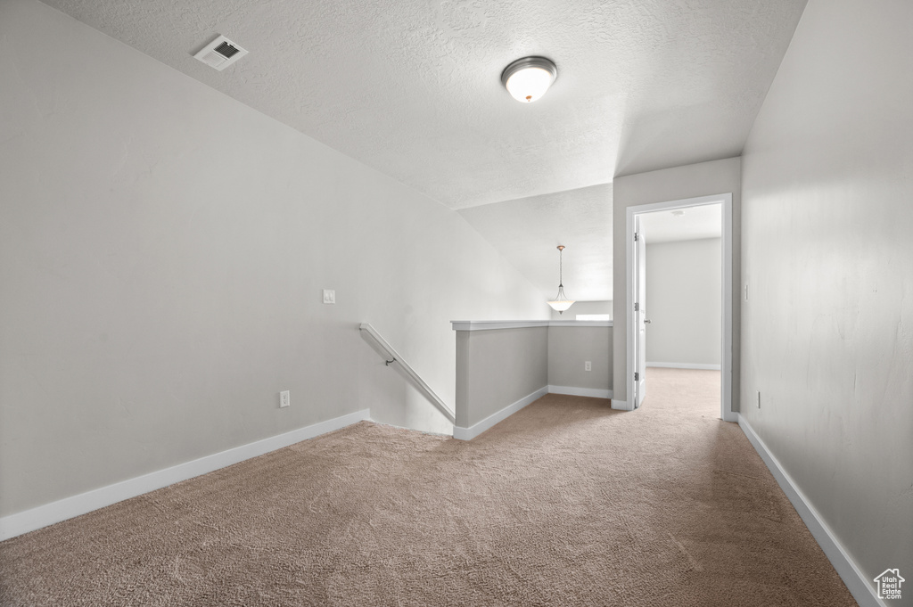 Spare room featuring a textured ceiling, carpet flooring, and baseboards
