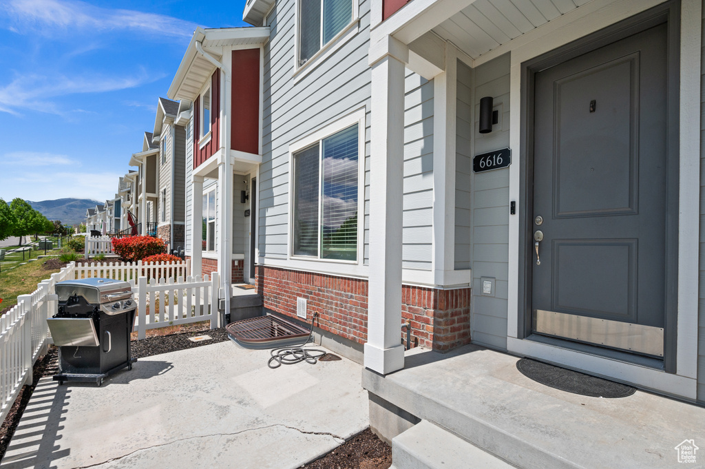 Entrance to property featuring covered porch, a mountain view, brick siding, and fence