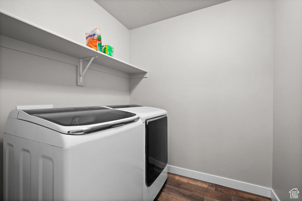 Laundry area with separate washer and dryer, dark wood-style floors, and baseboards