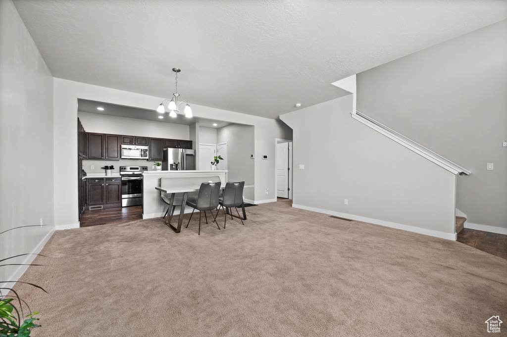 Living area with light carpet, a chandelier, baseboards, and stairs