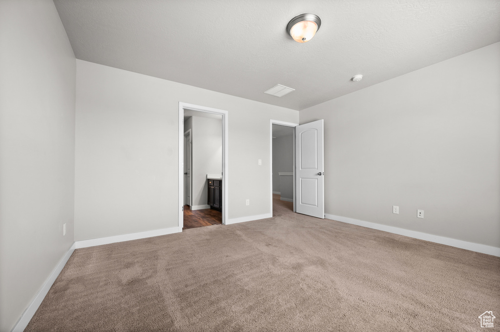 Unfurnished bedroom featuring carpet flooring, baseboards, and connected bathroom