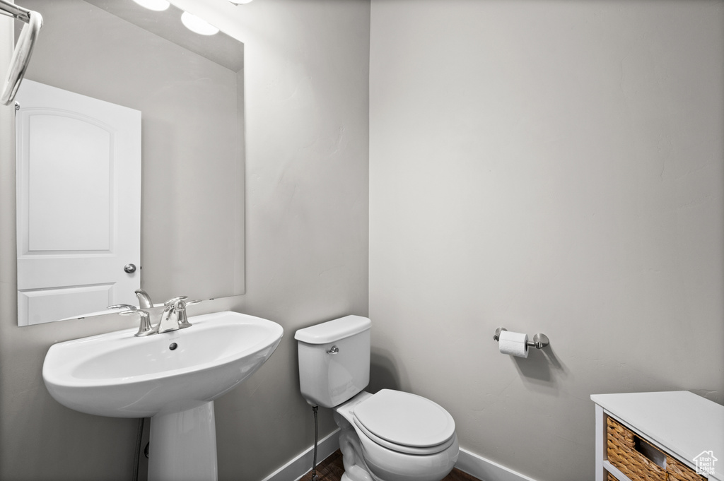 Bathroom with toilet, baseboards, and a sink