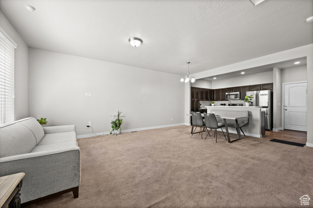 Living room with light carpet, baseboards, recessed lighting, and a chandelier