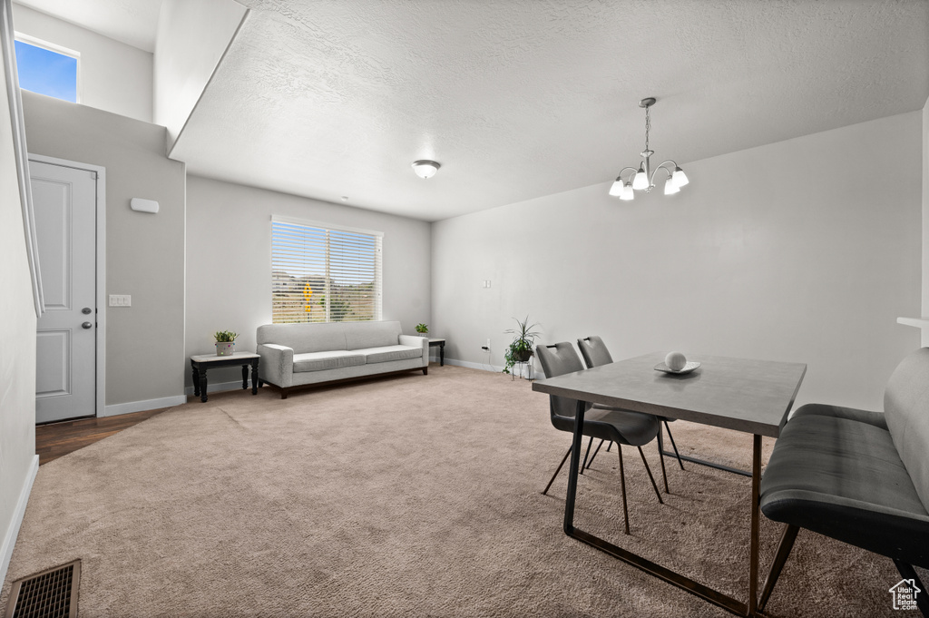 Dining area featuring a chandelier, carpet, baseboards, healthy amount of natural light, and a textured ceiling