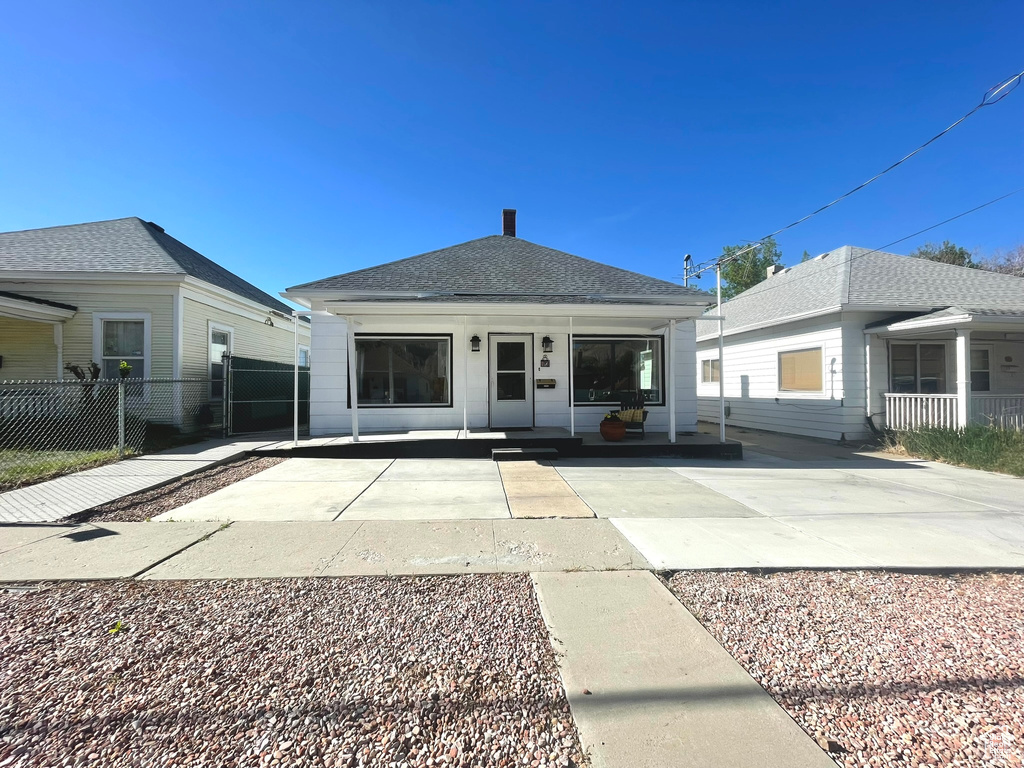 Back of house featuring fence, a porch, and roof with shingles