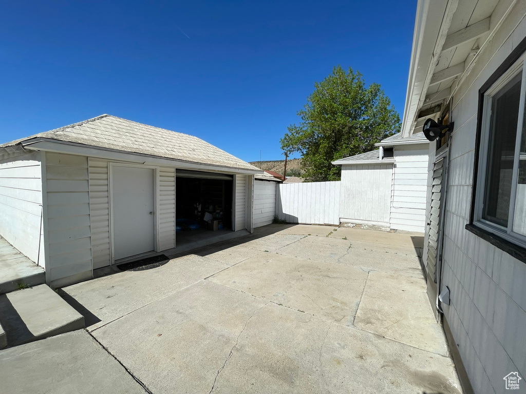 View of patio / terrace featuring an outbuilding, fence, and a garage