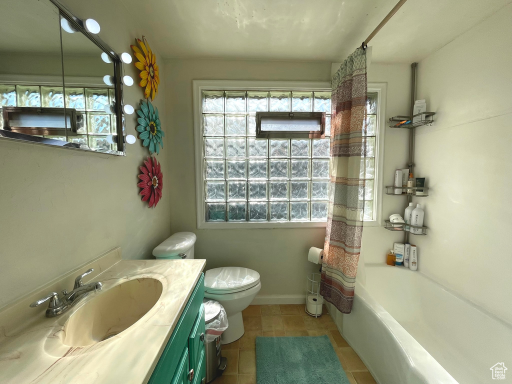 Bathroom featuring plenty of natural light, tile patterned floors, vanity, and toilet