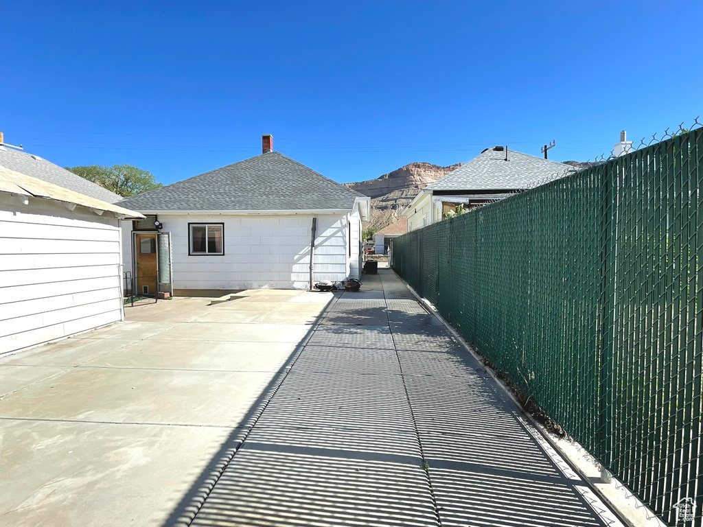 Rear view of property with fence, a patio, and a shingled roof