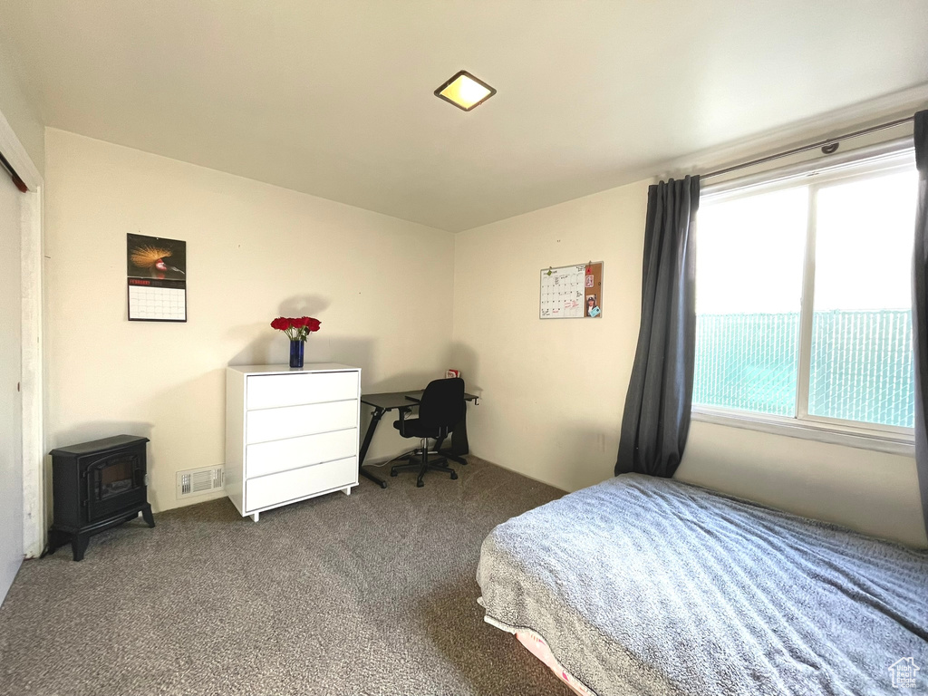 Bedroom featuring a wood stove and carpet flooring