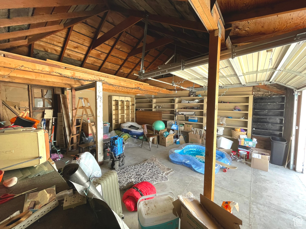 Misc room with lofted ceiling, a garage, and unfinished concrete flooring