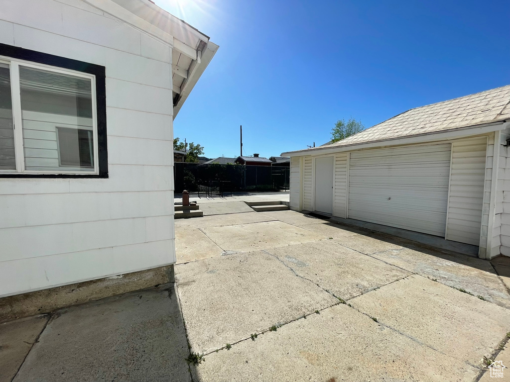 View of property exterior with a patio, fence, and an outdoor structure