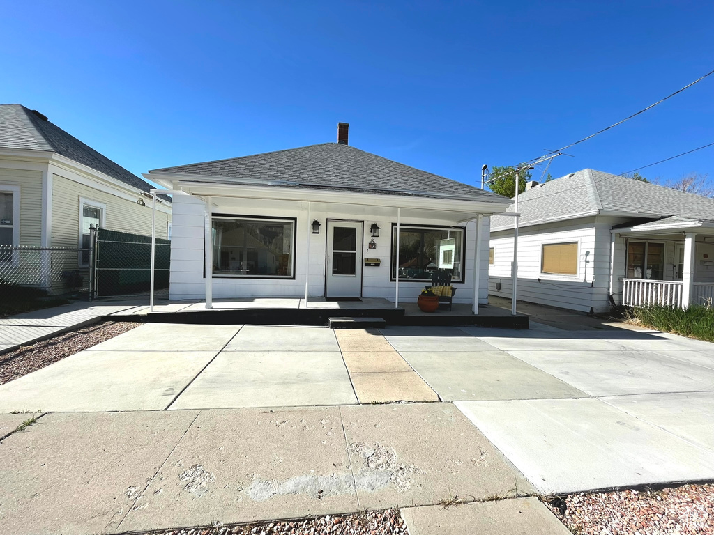 View of front of home with a porch, fence, and roof with shingles