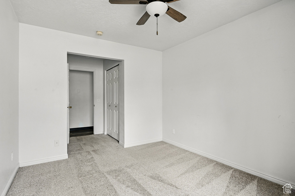 Empty room featuring a ceiling fan, carpet, baseboards, and a smoke detector