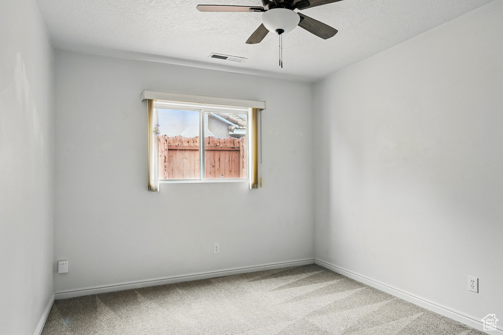 Unfurnished room with ceiling fan, carpet, baseboards, and a textured ceiling
