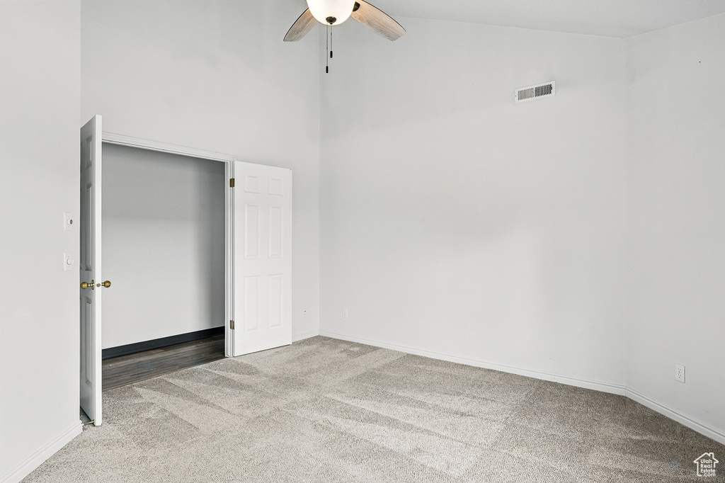 Unfurnished bedroom featuring carpet floors, high vaulted ceiling, baseboards, and a ceiling fan