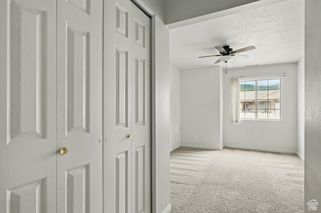 Unfurnished bedroom featuring carpet flooring, baseboards, a textured ceiling, and a ceiling fan