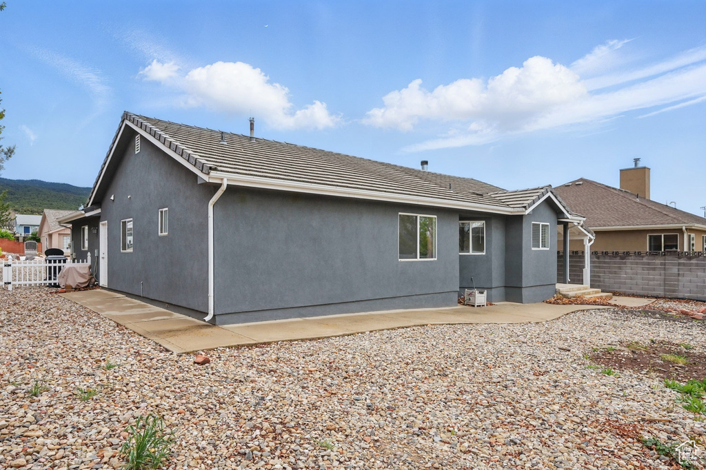 Back of property with fence, stucco siding, and a patio area