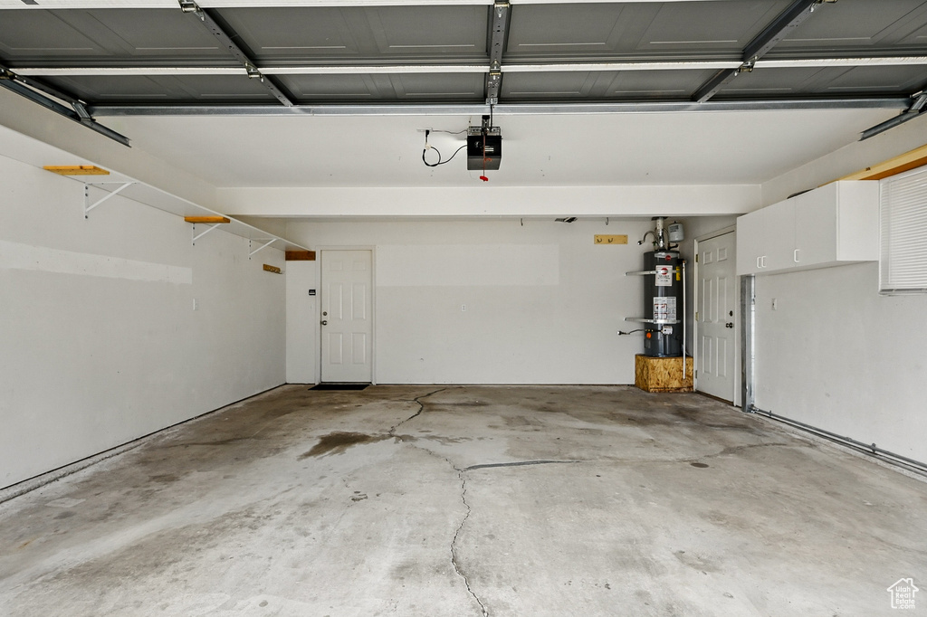 Garage featuring secured water heater and a garage door opener
