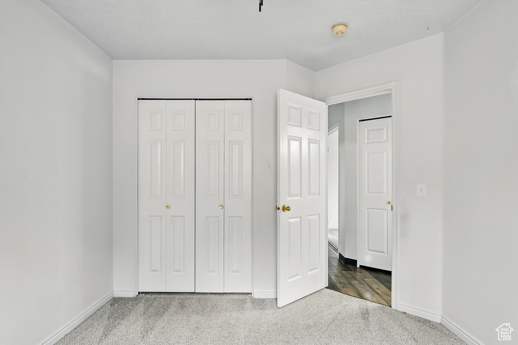 Unfurnished bedroom featuring carpet flooring, baseboards, and a closet