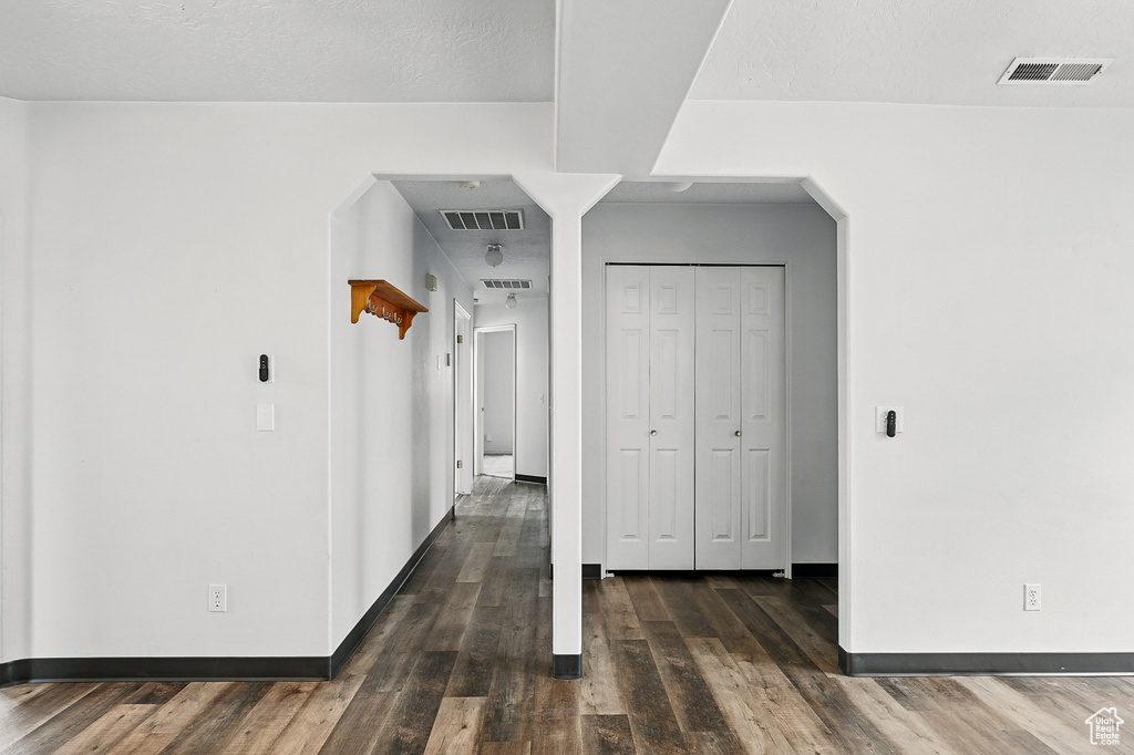 Hall featuring wood finished floors, arched walkways, and baseboards