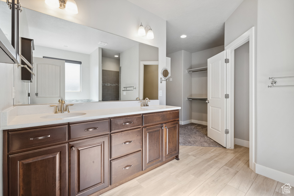 Bathroom with double vanity, wood finished floors, and baseboards