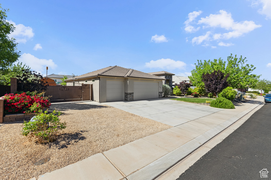 View of front facade featuring an attached garage, concrete driveway, a gate, stucco siding, and fence