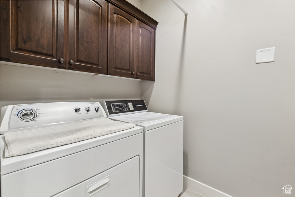 Laundry room with washer and clothes dryer, cabinet space, and baseboards