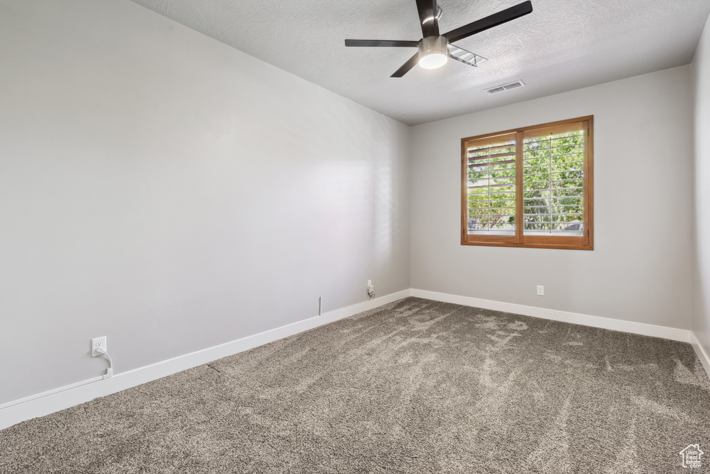 Empty room with ceiling fan, carpet flooring, a textured ceiling, and baseboards