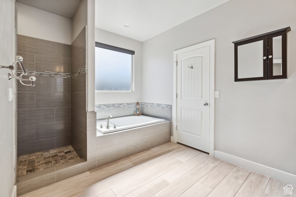 Bathroom featuring a bath, tiled shower, and wood finished floors
