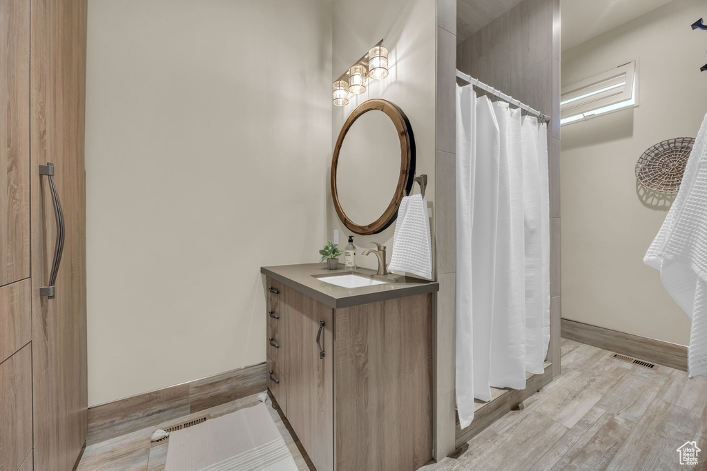 Full bathroom featuring vanity, a shower with shower curtain, baseboards, and wood finished floors