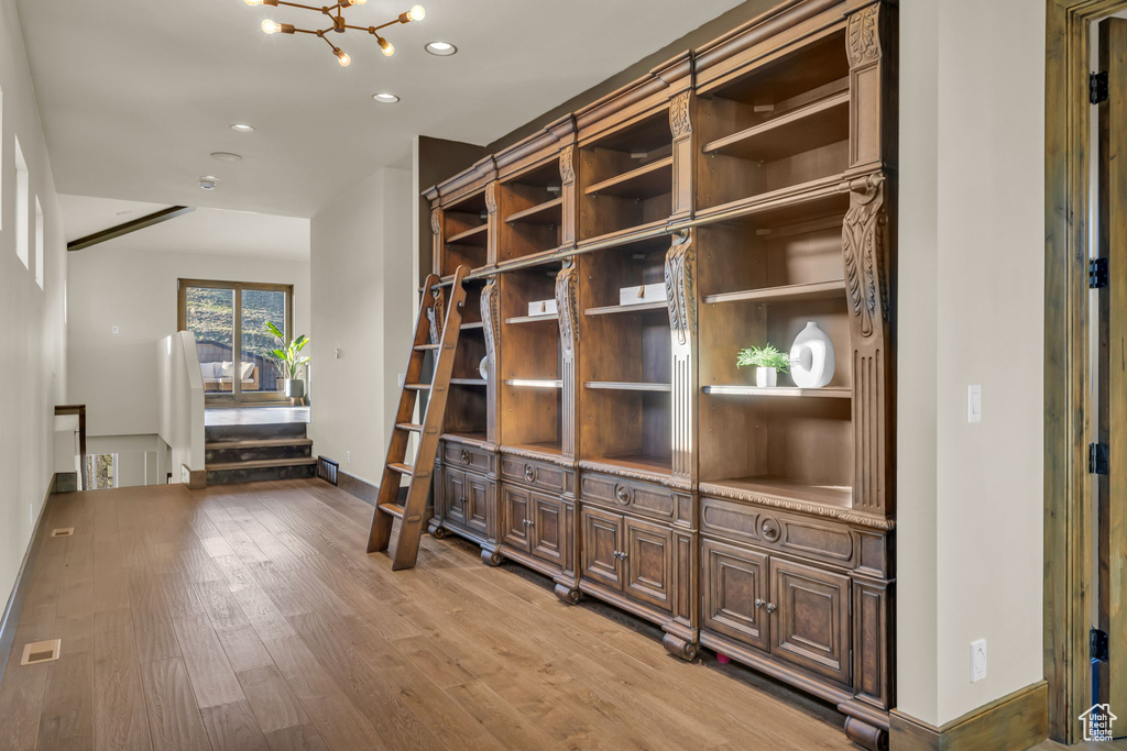 Hall featuring light wood-style floors, a chandelier, recessed lighting, and baseboards