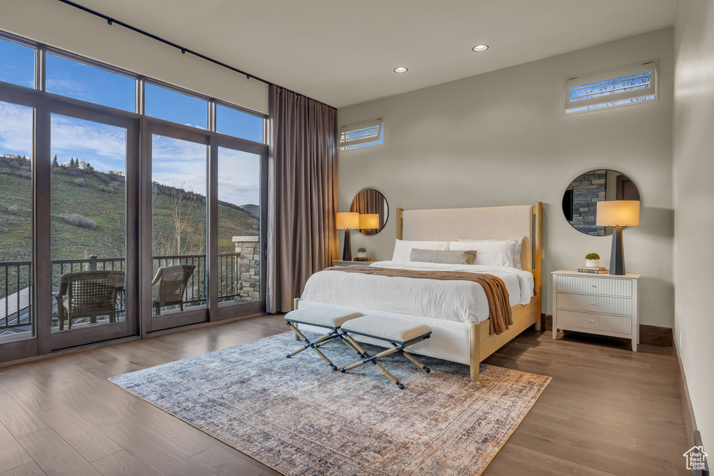 Bedroom with access to exterior, recessed lighting, multiple windows, wood finished floors, and baseboards