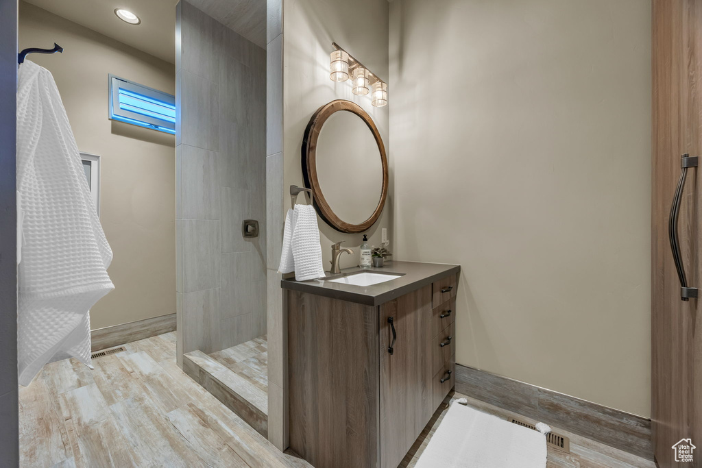 Bathroom featuring walk in shower, vanity, wood finished floors, and recessed lighting