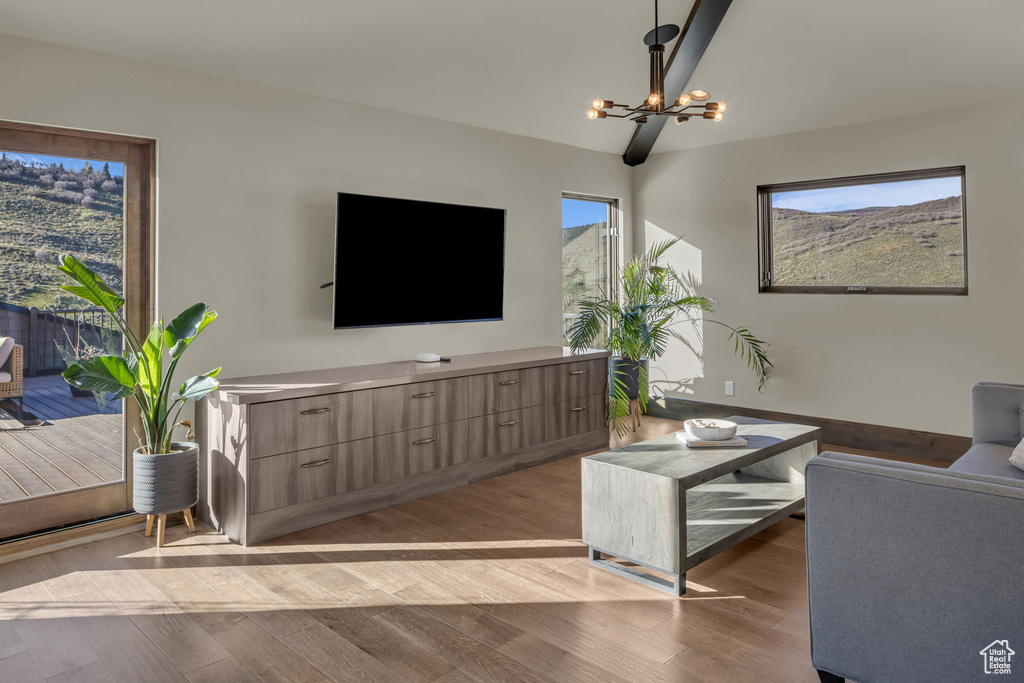 Living area with a chandelier, light wood finished floors, and lofted ceiling