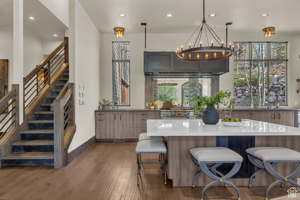 Kitchen featuring wood finished floors, recessed lighting, plenty of natural light, a sink, and a breakfast bar