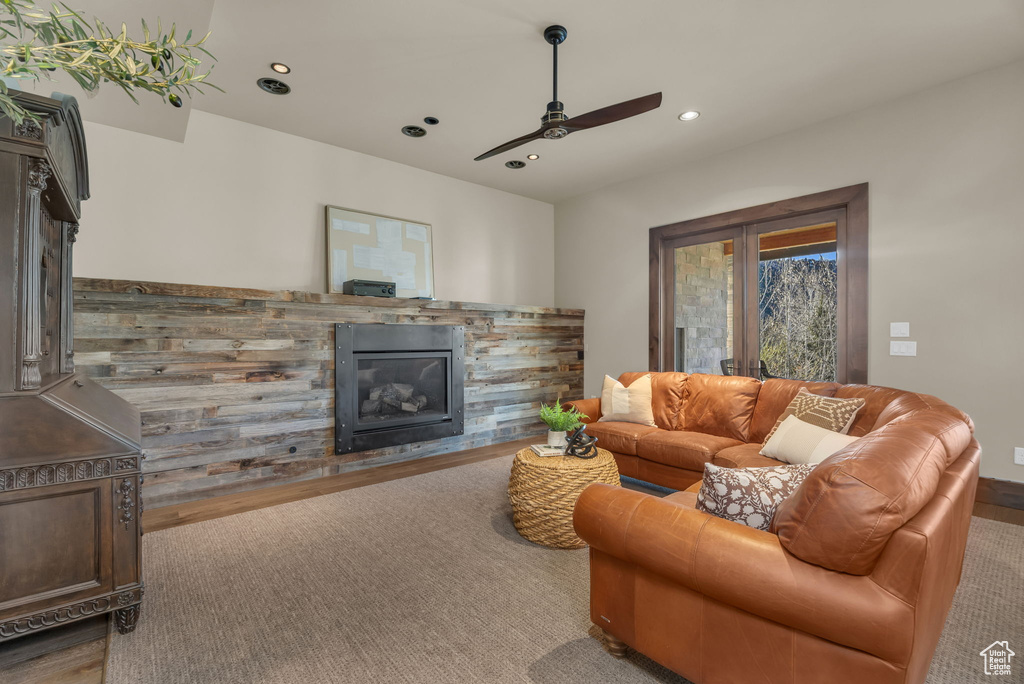 Living area featuring a glass covered fireplace, a ceiling fan, recessed lighting, and wood finished floors